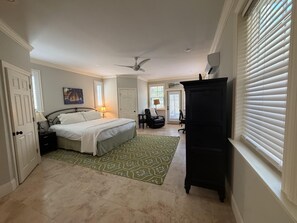 A bedroom with a bed, a desk, a chair, a standing lamp, and a ceiling fan. - Endless Summer House , Lagoon Pool, Private Beach, Bikes (Inlet Beach)