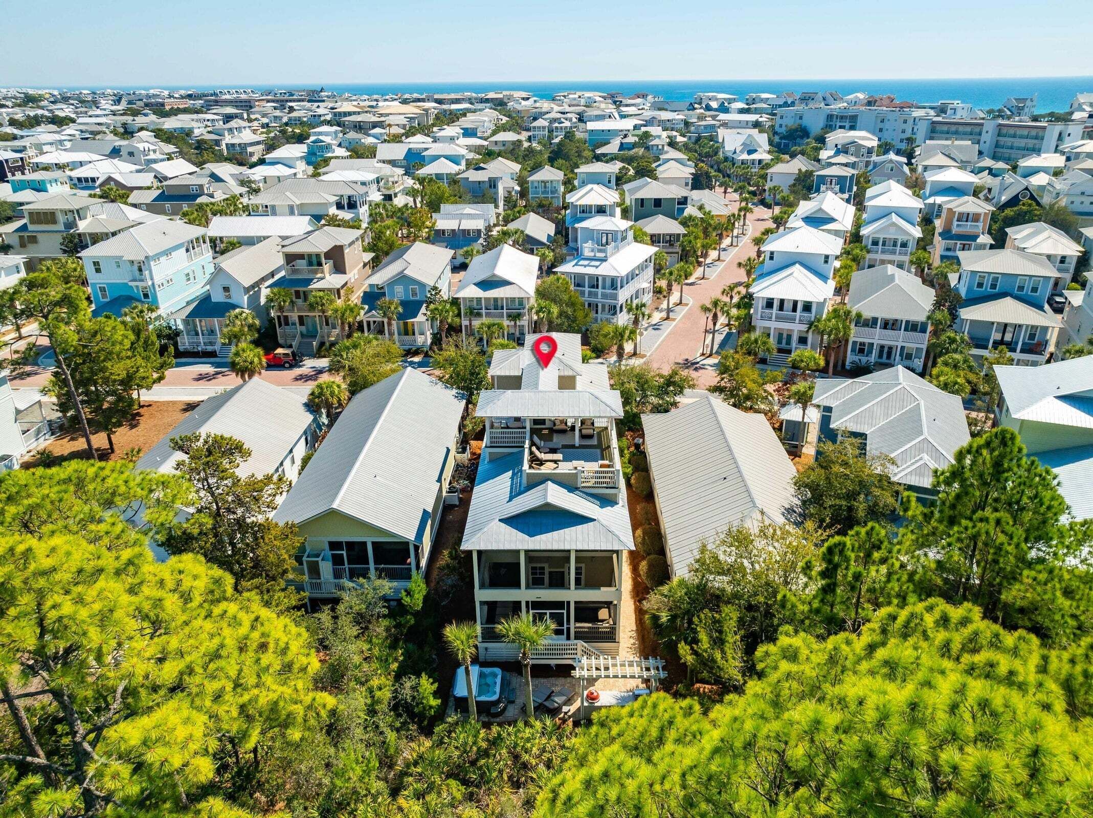 A coastal residential area with multiple two-story houses, a central road, and a view of the ocean.