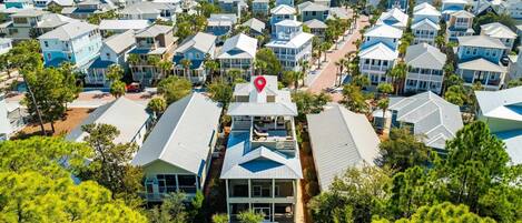 A coastal residential area with multiple two-story houses, a central road, and a view of the ocean.