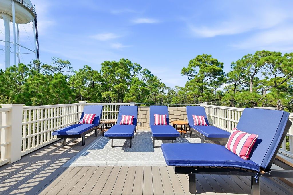 A deck with lounge chairs and a white railing.