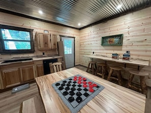 Una cocina con armarios de madera, un tablero de juego de cuadros y una barra con taburetes.