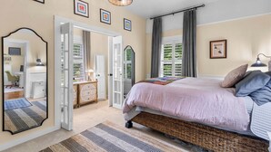 Ein Schlafzimmer mit einem großen Bett, einem Spiegel, einer Kommode und einer Tür, die auf einen Balkon führt.