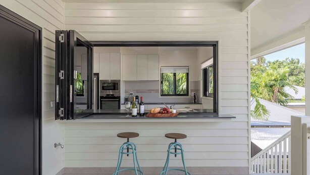 Una cocina moderna con un ventanal amplio, dos taburetes de bar y vistas al exterior.