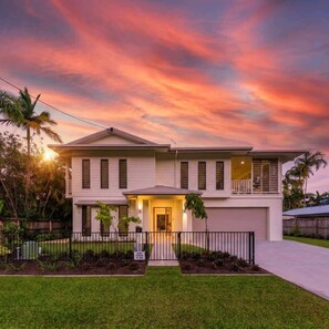 A two-story house with a front porch, a garage, and a well-maintained lawn. - Papaya Beach House - Port Douglas (Port Douglas)