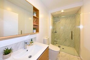 Ein modernes Badezimmer mit einem großen Spiegel, zwei Waschbecken, einer Toilette und einer Duschkabine.