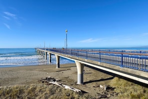 A coastal pier with a blue railing, concrete supports, and a clear sky. - Coastal 1BR Retreat – Steps to New Brighton Beach (Christchurch)