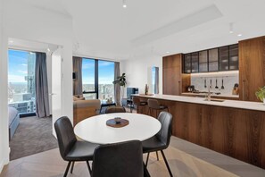 Un appartement moderne comprenant un coin repas, une cuisine et une grande fenêtre donnant sur la ville.