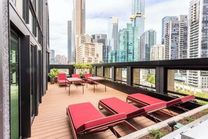 Une terrasse sur le toit avec des fauteuils rouges, une plateforme en bois et une vue imprenable sur les toits de la ville.