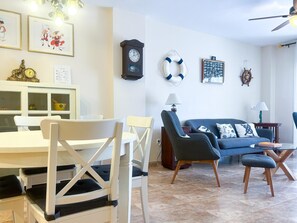 Un salon comprenant une table à manger, des chaises, un canapé et une horloge au mur.
