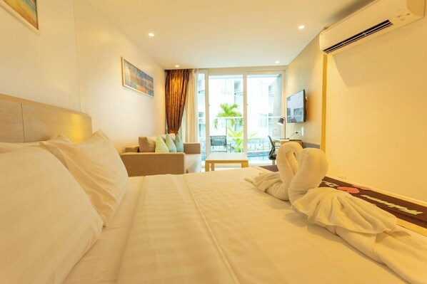 A hotel room with a bed, a sofa, a TV, and a balcony with a view. - Bachfront Seaside Escape Pool Access C109 (Tambon Rawai)