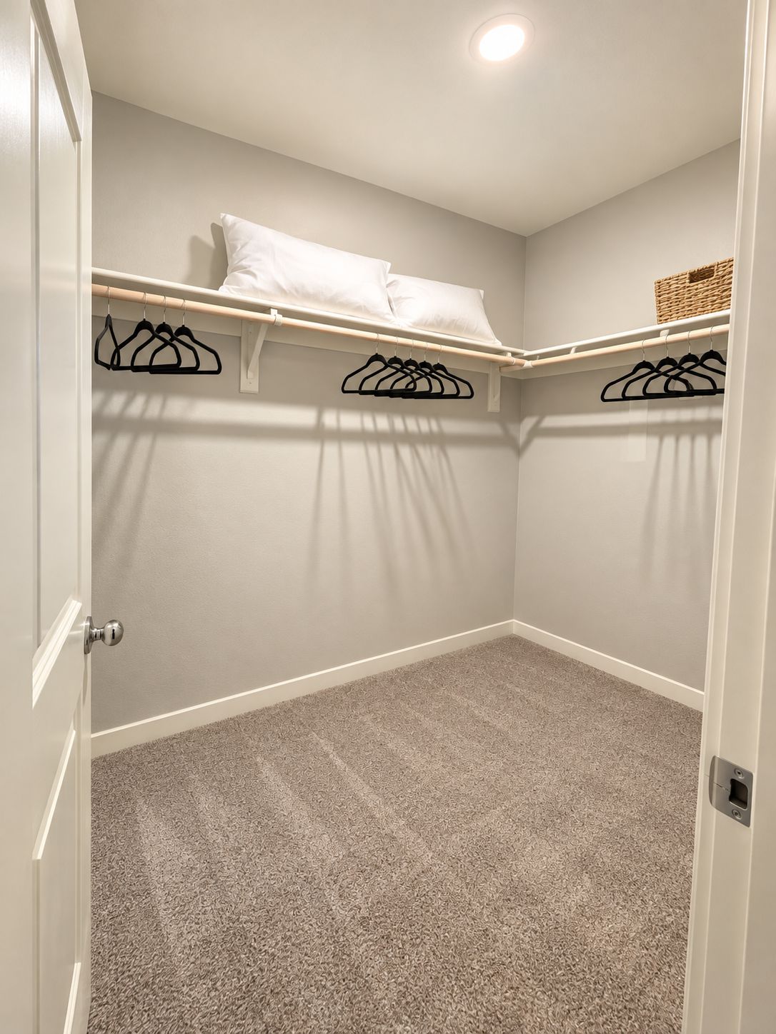A closet with hanging space, a shelf with a basket, and a door with a handle.