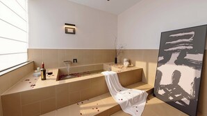 A modern bathroom with a bathtub, a towel, rose petals, a wine bottle, and a glass. - Wuye WOO YEAH Tangchi Hotel (Leshan)