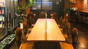 A restaurant with a long wooden table, black chairs, a coffee bar, and a sign for a cooking room. - Hotel Livemax Yokohama Station West Exit (Yokohama)