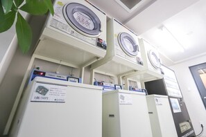 Une rangée de machines à laver empilées dans une pièce dont la porte se trouve à droite.