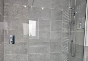 Eine moderne Dusche mit Handbrause und Armaturen an der Wand.