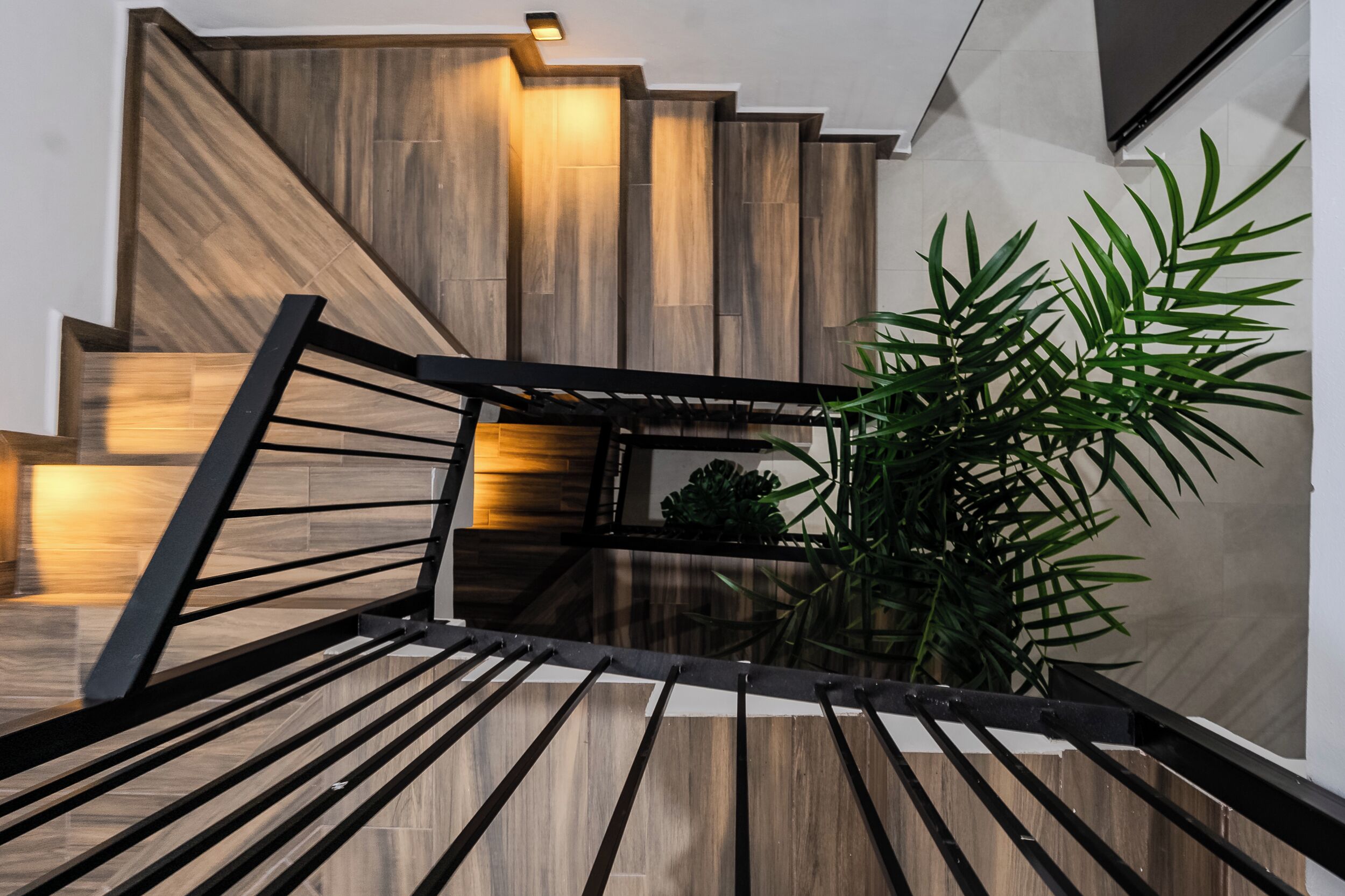 Eine moderne Treppe mit Holzstufen und schwarzen Geländern, die zu einer oberen Ebene führt.