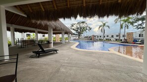 Un espace piscine comprenant des chaises longues, un coin salon abrité et une piscine.