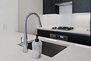 Eine moderne Küche mit einem Edelstahl-Wasserhahn, einer Marmor-Spüle und einer digitalen Bedienoberfläche.