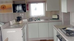 Una cucina compatta con forno a microonde, tostapane, lavello e fornello.