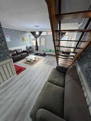 A living room with a sofa, a coffee table, a pool table, and a staircase. - House Of Comfort in London (Greater London)
