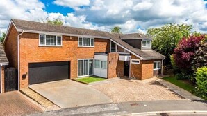 Una casa a due piani in mattoni con garage, vialetto d'accesso e prato curato.