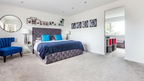 Una camera da letto moderna con un letto grande, un comodino, una sedia, uno specchio e opere d'arte alle pareti.