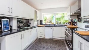 Cucina moderna con mobili bianchi, piano di lavoro nero e finestra con vista su spazi verdi.
