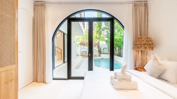 A modern bedroom with a large bed, a view of a pool, and a tropical outdoor setting. - Casa Myla Villa - Bingin Bali (Munggu)