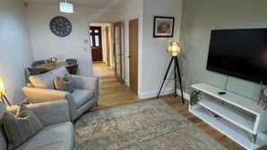 Un salon avec un canapé, une télévision, une lampe et un tapis.