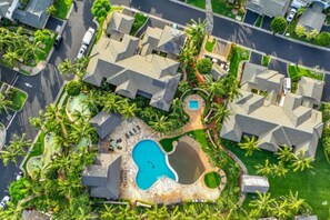 Eine Luftaufnahme eines Wohngebiets mit mehreren Häusern, einem Swimmingpool und Palmen.