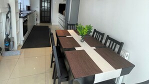 A dining area with a long table, chairs, and a kitchen in the background. - Tottenham - Sleeps 10 - Garden - Near Transport (London)