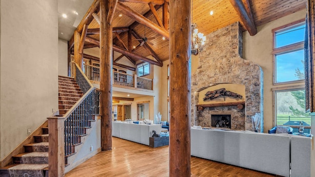 Un intérieur spacieux agrémenté d’un escalier en bois, d’une cheminée en pierre et d’un balcon offrant une vue panoramique.