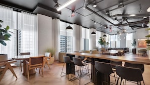 Un espacio de oficina moderno con una larga mesa de madera, varias sillas y una zona de bar.