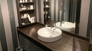 A bathroom with a round sink, a mirror, and a shelf with toiletries. - GOOD HOTEL OSAKA (Toyonaka)