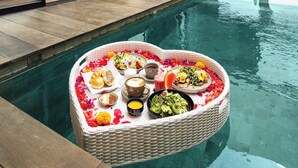 Una habitación de hotel moderna con piscina, una zona de comedor junto a la piscina y una cama.