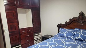 Een slaapkamer met een bed, een kledingkast en een nachtkastje.