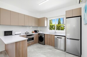 A modern kitchen with a stainless steel refrigerator, built-in oven, microwave, and dishwasher. - Villa Haven by Ezoria Villas (Paphos)