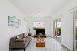 A modern living room with a sofa, coffee table, and artwork on the wall. - Villa Haven by Ezoria Villas (Paphos)