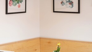 Un coin salon avec une table blanche et un meuble blanc, des œuvres d’art florales encadrées aux murs et un luminaire suspendu.
