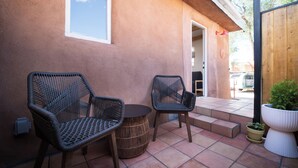 Une terrasse extérieure avec des chaises en osier, une table ronde et une plante en pot.