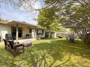 Ein Haus mit überdachter Terrasse, Gartenmöbeln und einem umzäunten Grundstück.