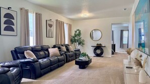 A living room with a black leather sofa, a round coffee table, and a plant. - Stunning 4BR Pool Home Your Private Oasis Awaits (Davenport)