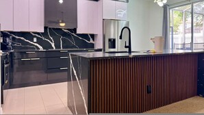 A modern kitchen with a marble countertop, stainless steel appliances, and a wooden island. - Stunning 4BR Pool Home Your Private Oasis Awaits (Davenport)