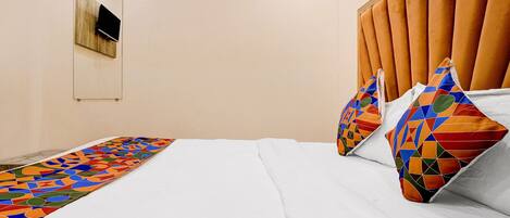 A neatly made bed with a colorful geometric-patterned runner, a headboard with vertical slats, and two pillows with a geometric design.