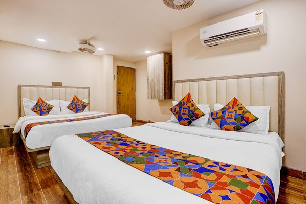 A hotel room with two beds, a wooden floor, an air conditioning unit, and a door. - FabHotel Pride Suitz (Mumbai)