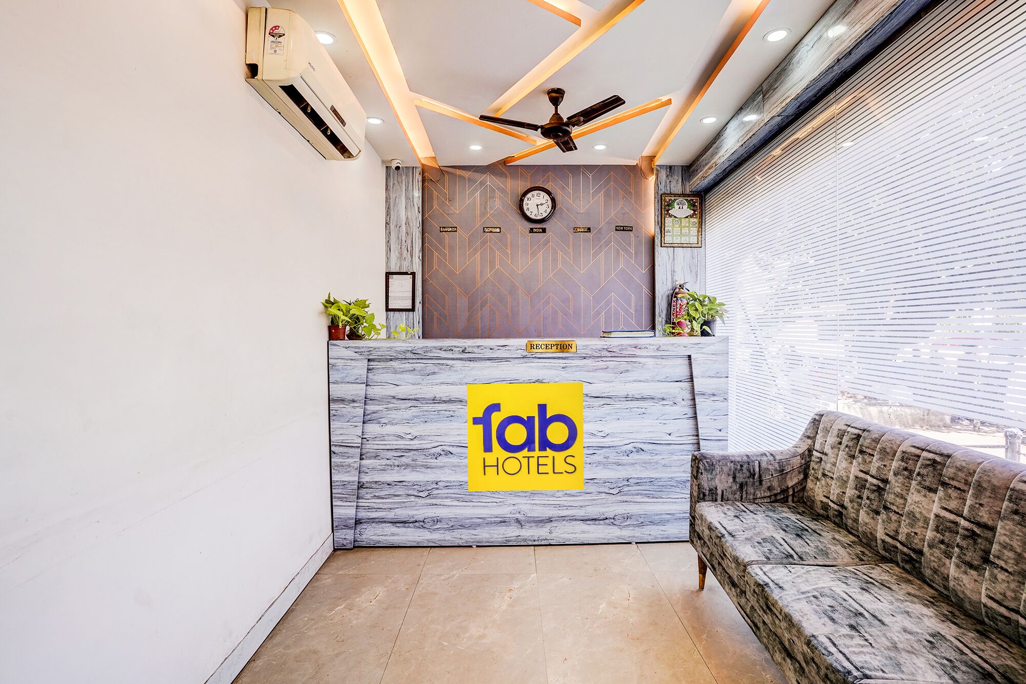 A reception desk with a 'fab hotels' sign, a clock, and a ceiling fan.