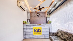 A reception desk with a 'fab hotels' sign, a clock, and a ceiling fan. - FabHotel Pride Suitz (Mumbai)