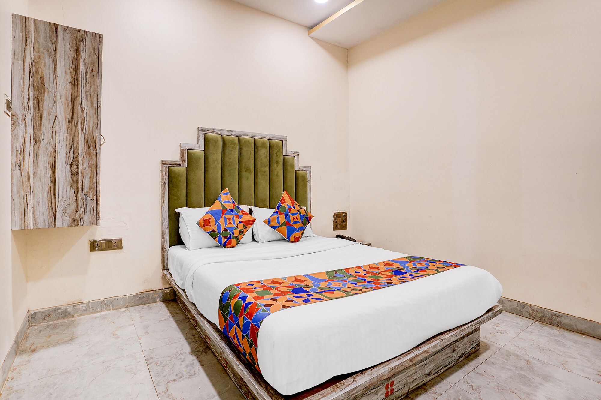 A bedroom with a bed, a headboard, a wall-mounted artwork, and a tiled floor.