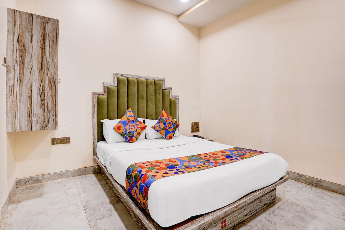 Un dormitorio con cama, cabecera, una obra de arte en la pared y suelo de baldosas.