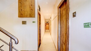 A hallway with wooden doors, an exit sign, and a staircase. - FabHotel Pride Suitz (Mumbai)